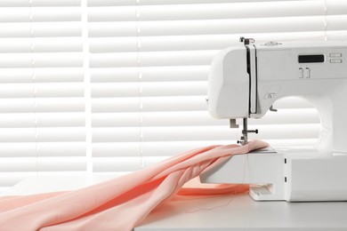 Photo of Sewing machine and fabric on white table indoors