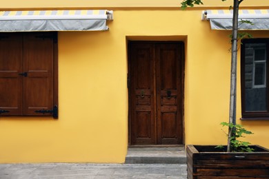 View of building with wooden door and sun blinds over windows . Exterior design