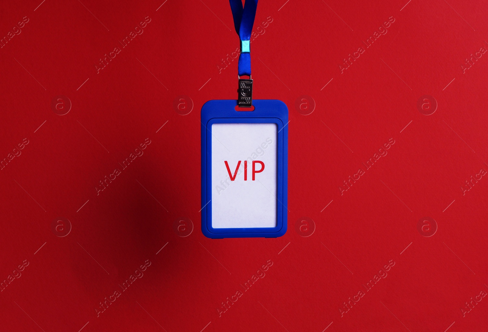 Photo of Blue plastic vip badge hanging on red background