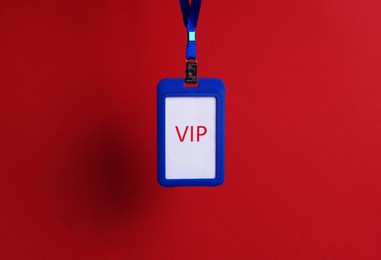 Blue plastic vip badge hanging on red background