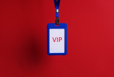 Photo of Blue plastic vip badge hanging on red background