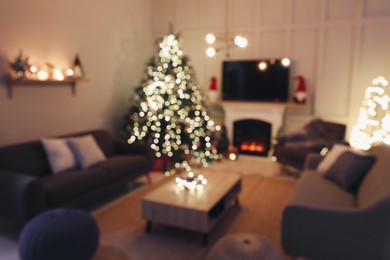 Photo of Blurred view of room with beautiful Christmas tree near fireplace