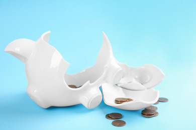 Photo of Broken piggy bank with coins on light blue background