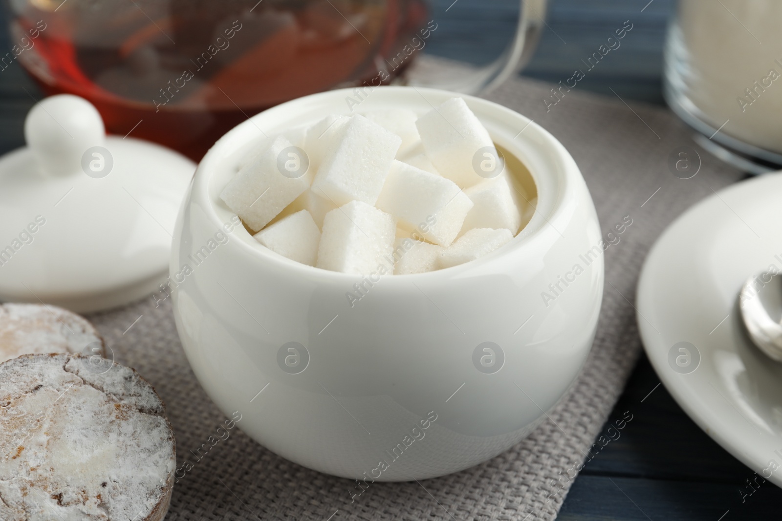 Photo of Refined sugar cubes in ceramic bowl on table