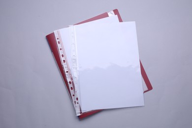 Photo of File folder with punched pockets and paper sheets on light grey background, top view