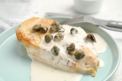 Photo of Delicious cooked chicken fillet with capers and sauce served on white table, closeup