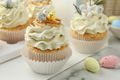 Photo of Tasty Easter cupcakes with vanilla cream on white marble table