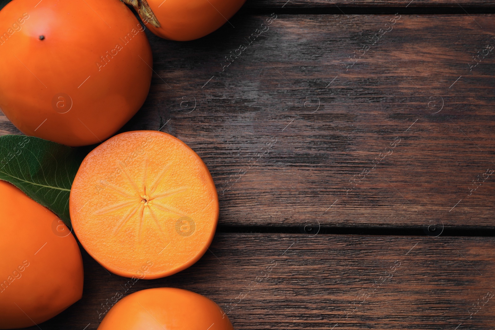 Photo of Delicious ripe persimmons on wooden table, flat lay. Space for text