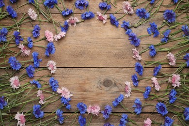 Photo of Frame of beautiful colorful cornflowers on wooden background, flat lay. Space for text