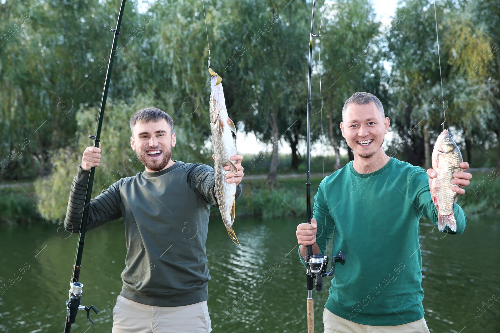 Photo of Friends with fishing rods and catch at riverside. Recreational activity