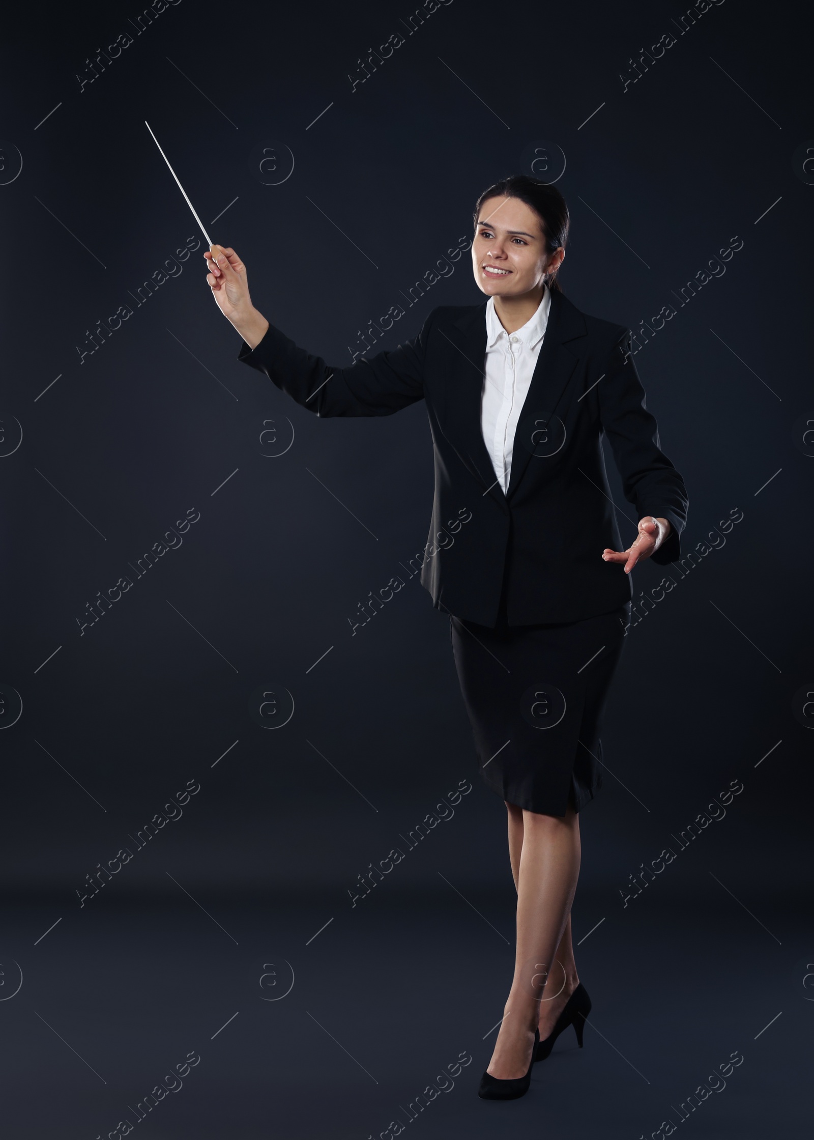 Photo of Happy young conductor with baton on dark background