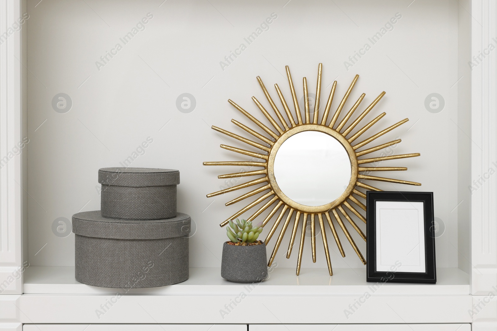 Photo of Grey decorative boxes, houseplant, mirror and frame on shelving unit