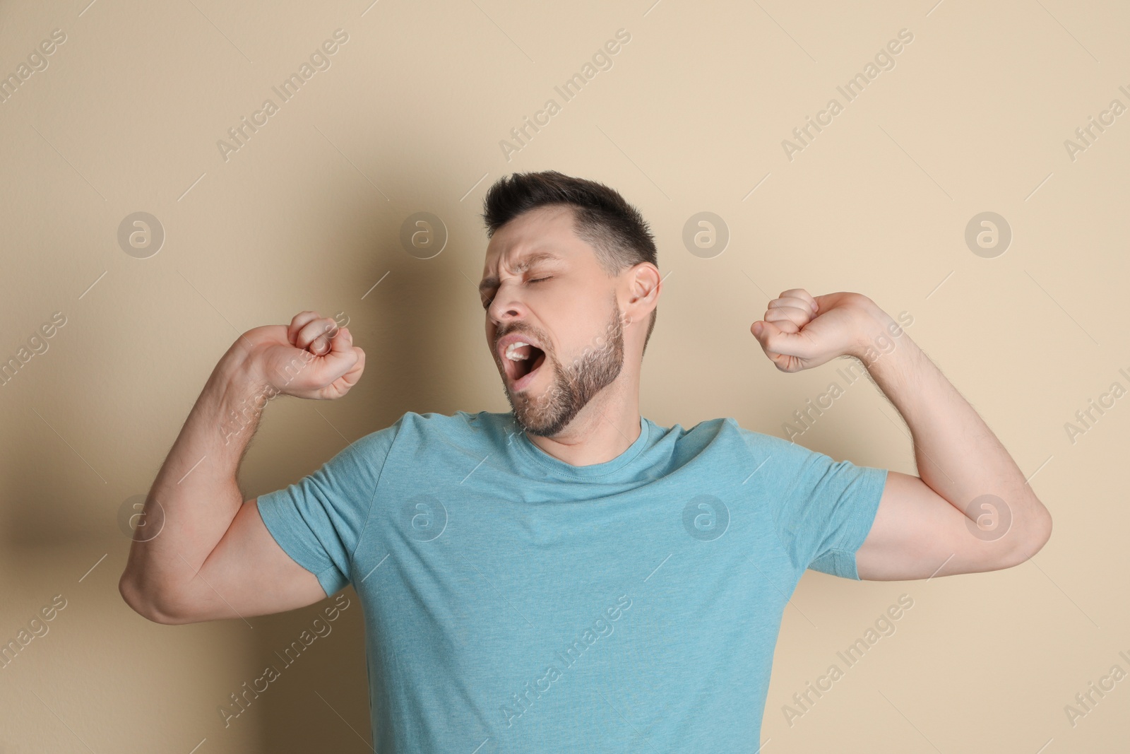 Photo of Portrait of sleepy man yawning on beige background