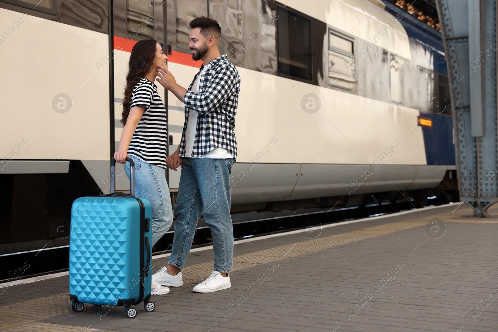 Photo of Long-distance relationship. Beautiful couple on platform of railway station, space for text