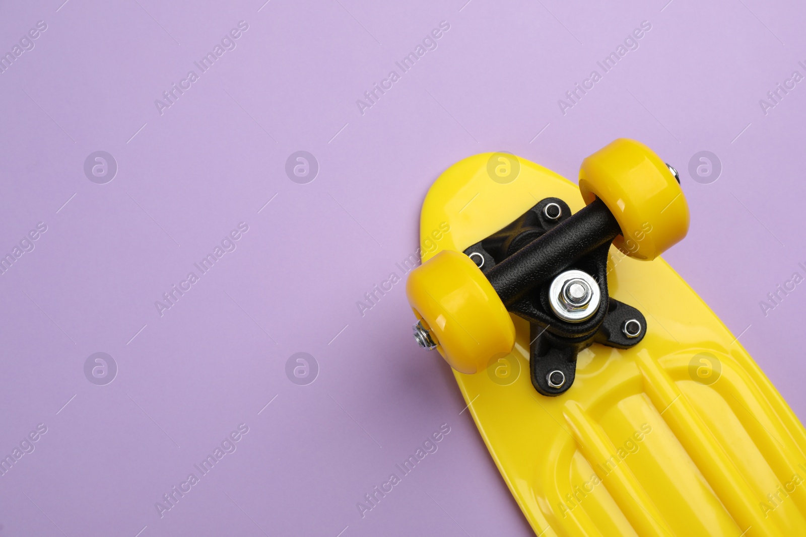 Photo of Skateboard on lilac background, top view. Space for text