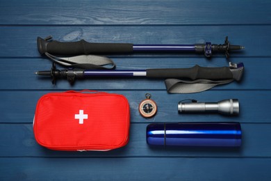 Photo of Flat lay composition with trekking poles and other hiking equipment on blue wooden background
