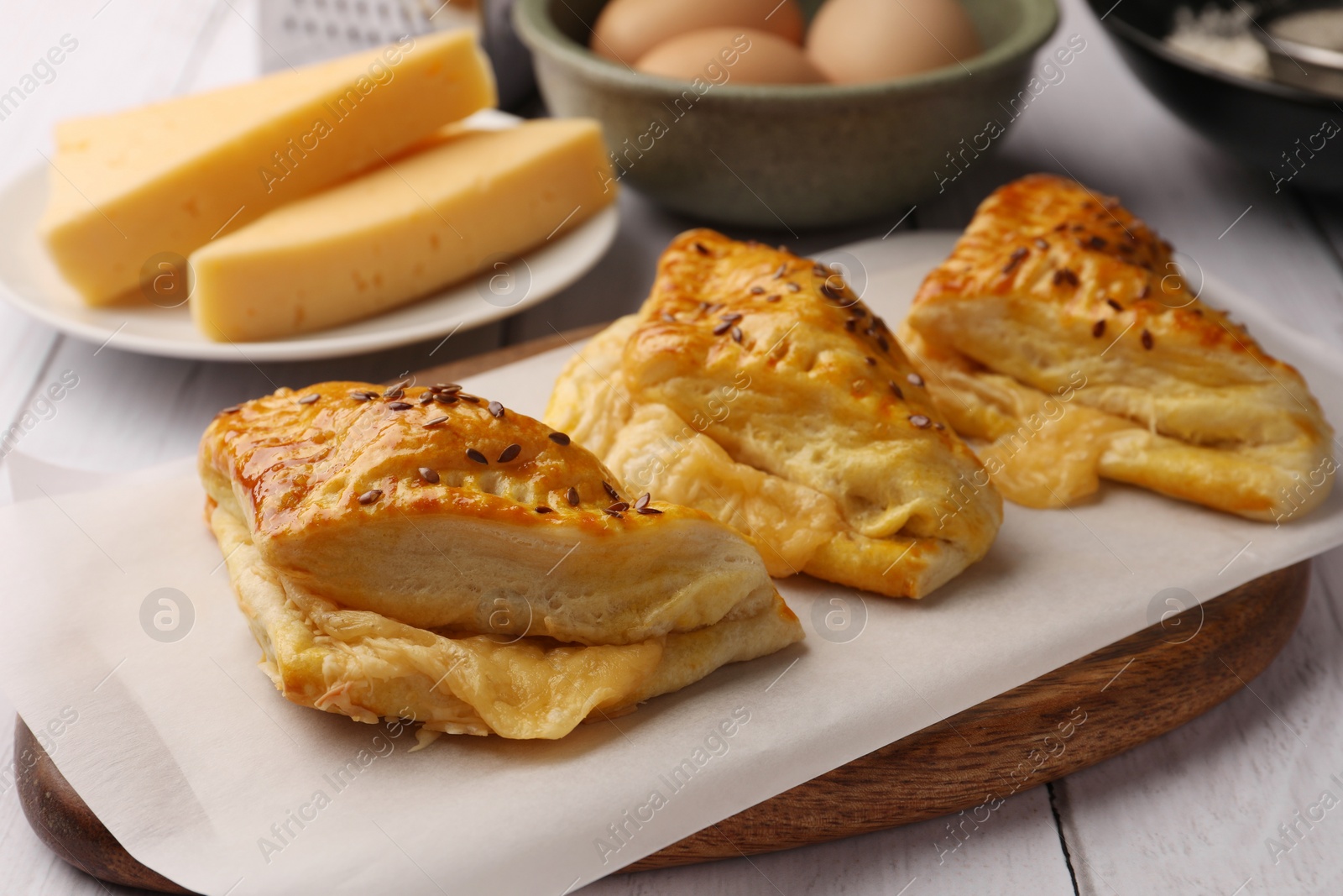 Photo of Fresh delicious puff pastry and ingredients on white wooden table, closeup