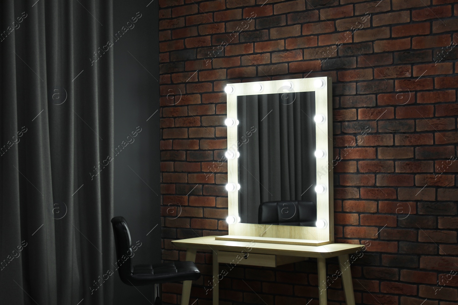 Photo of Mirror with light bulbs, table, chair and curtain in makeup room