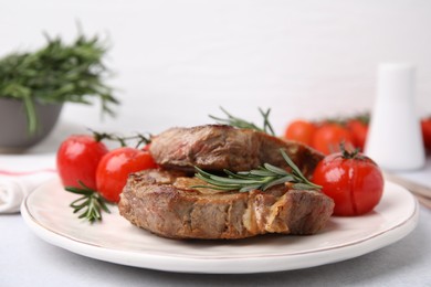 Photo of Delicious fried meat with rosemary and tomatoes on white table, closeup