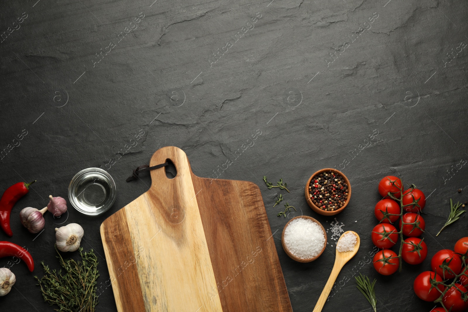 Photo of Flat lay composition with wooden cutting board and ingredients on black table, space for text. Cooking utensil