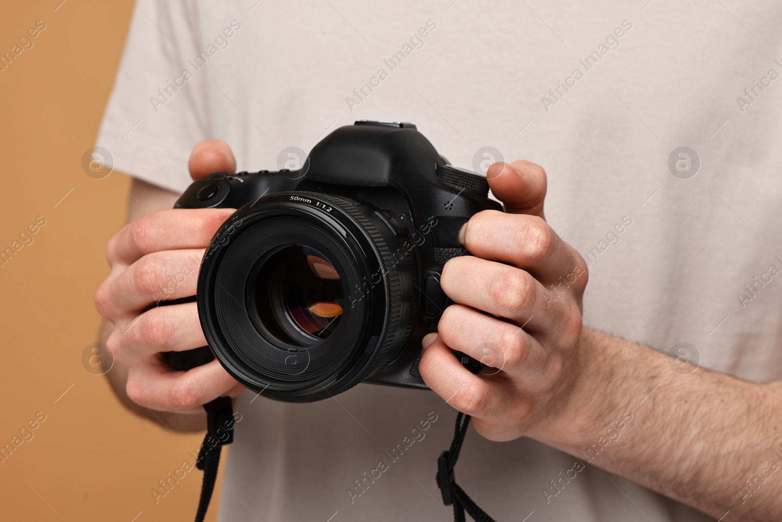 Photo of Photographer holding camera on beige background, closeup