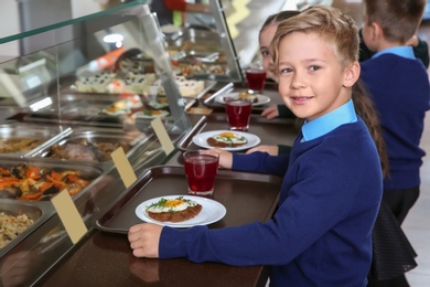 Photo of Children near serving line with healthy food in school canteen