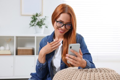 Photo of Happy young woman having video chat via smartphone at home