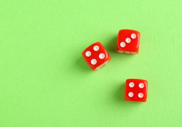 Photo of Three red game dices on green background, flat lay