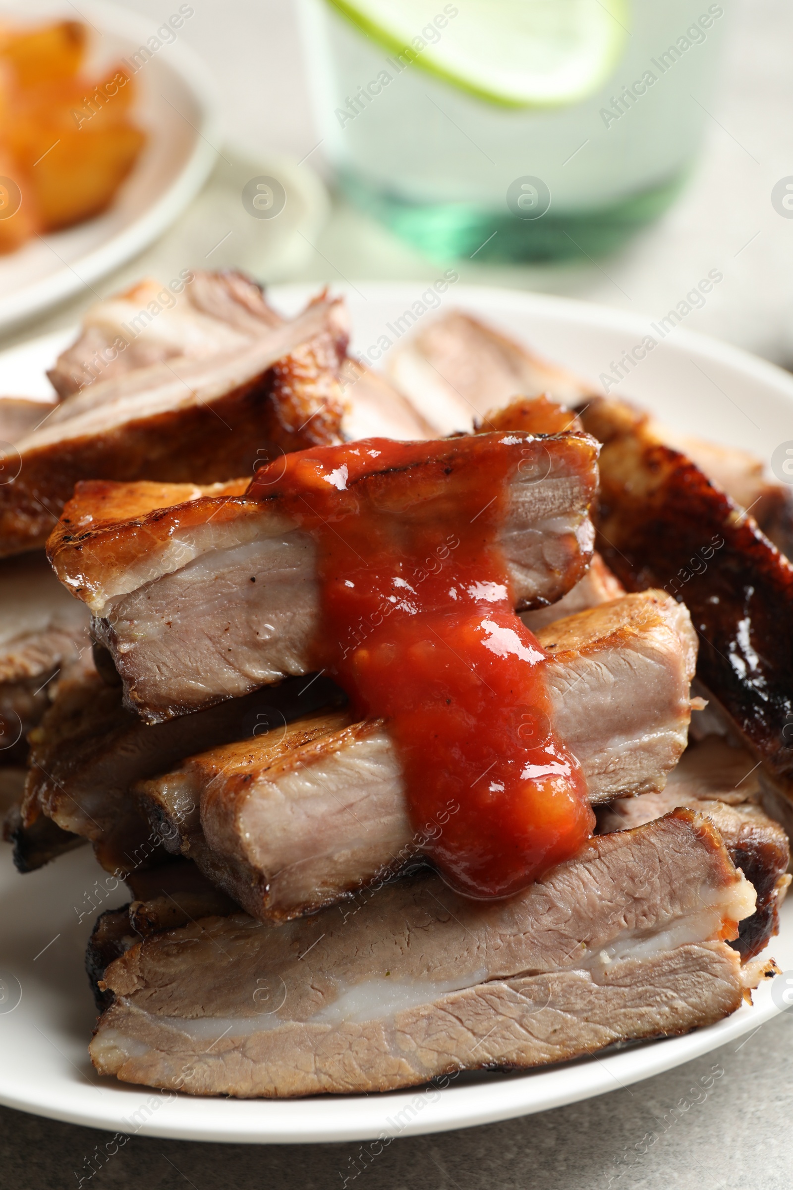 Photo of Delicious grilled ribs with sauce on table, closeup