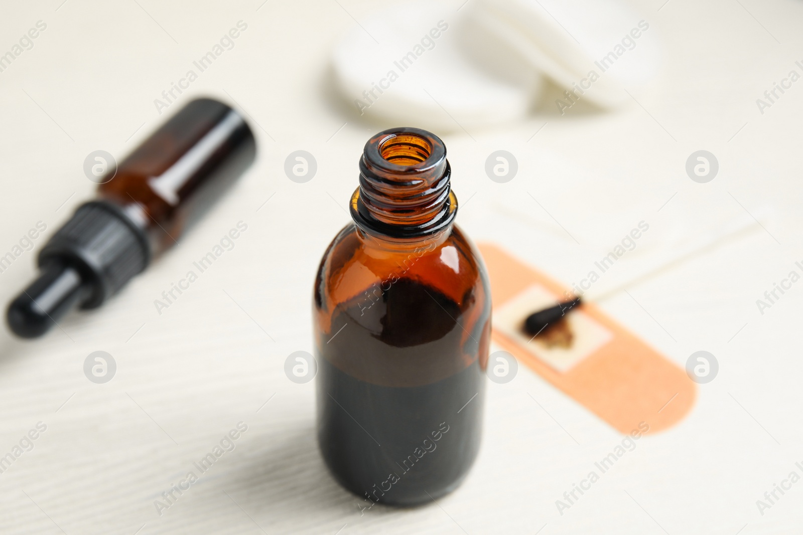 Photo of Bottle of medical iodine, sticking plaster and cotton bud on white wooden table, closeup