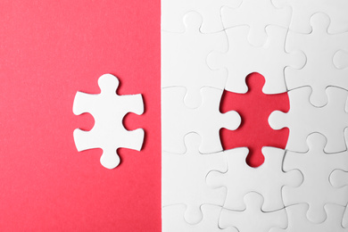 Blank white puzzle with separated piece on red background, flat lay