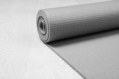 Rolled sports mat on wooden background. Space for text