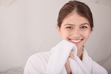 Photo of Beautiful teenage girl wiping face with towel at home, space for text