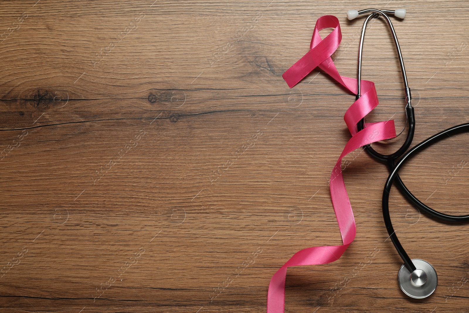 Photo of Breast cancer awareness. Pink ribbon and stethoscope on wooden table, flat lay. Space for text