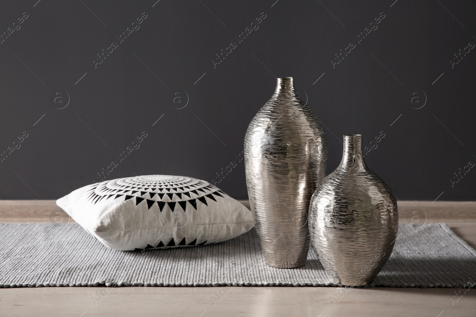 Photo of Beautiful vases and pillow on floor near black wall. Interior elements