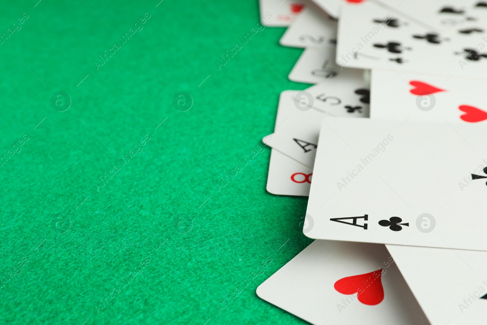 Photo of Deck of playing cards on green table, closeup. Space for text