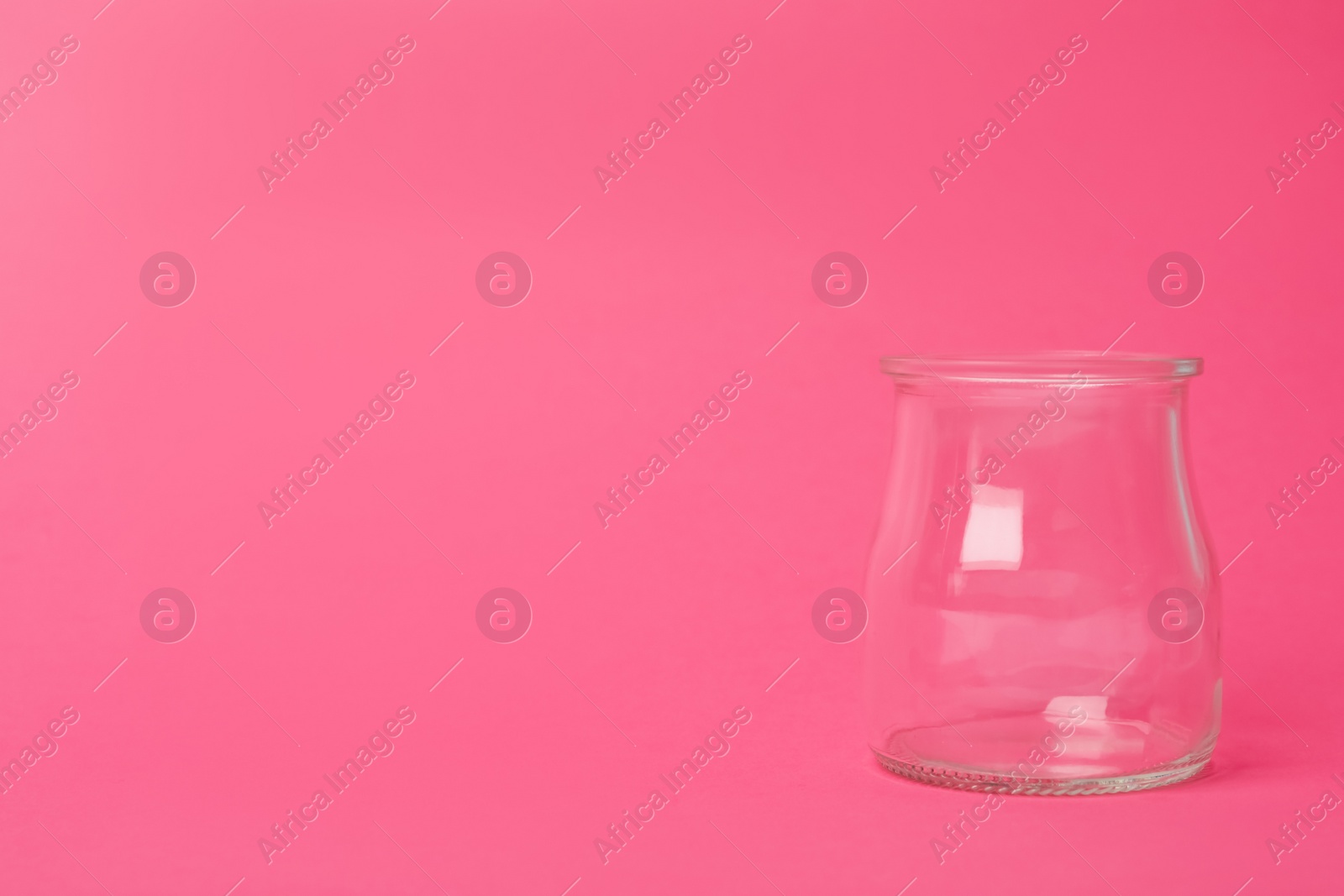 Photo of Open empty glass jar on pink background, space for text