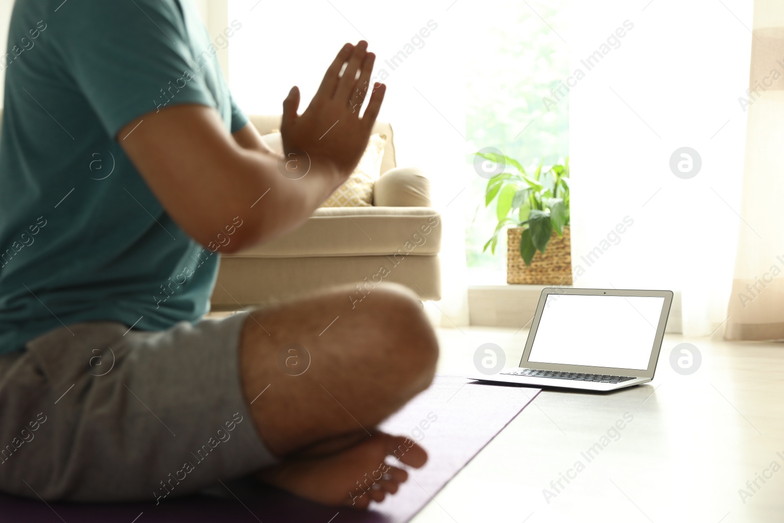 Photo of Man practicing yoga while watching online class at home during coronavirus pandemic, closeup. Social distancing