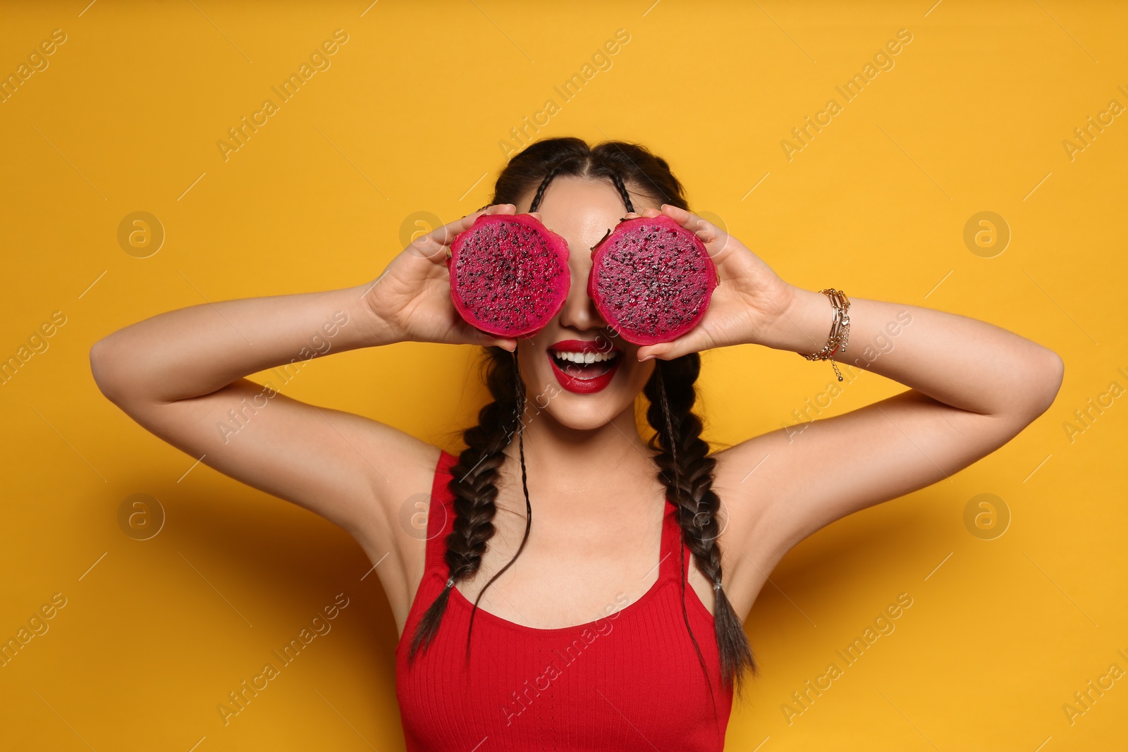 Photo of Young woman with fresh pitahaya on yellow background. Exotic fruit