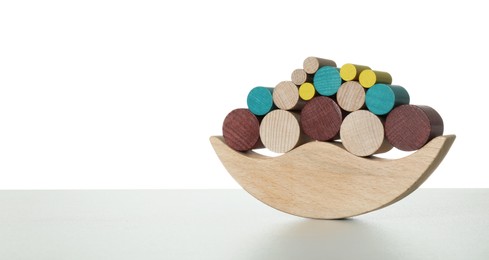 Photo of Wooden balance toy on light grey table against white background, space for text. Children's development