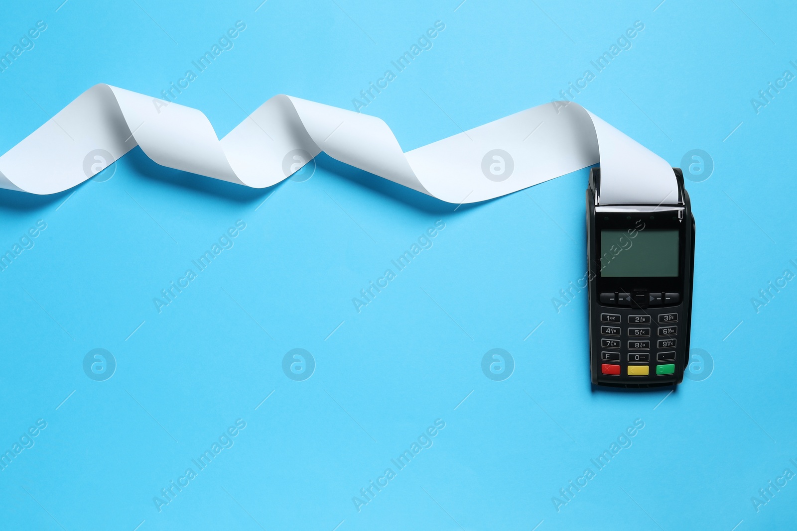 Photo of Payment terminal with thermal paper for receipt on light blue background, top view. Space for text