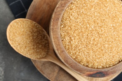 Photo of Brown sugar in bowl and spoon on grey table, top view