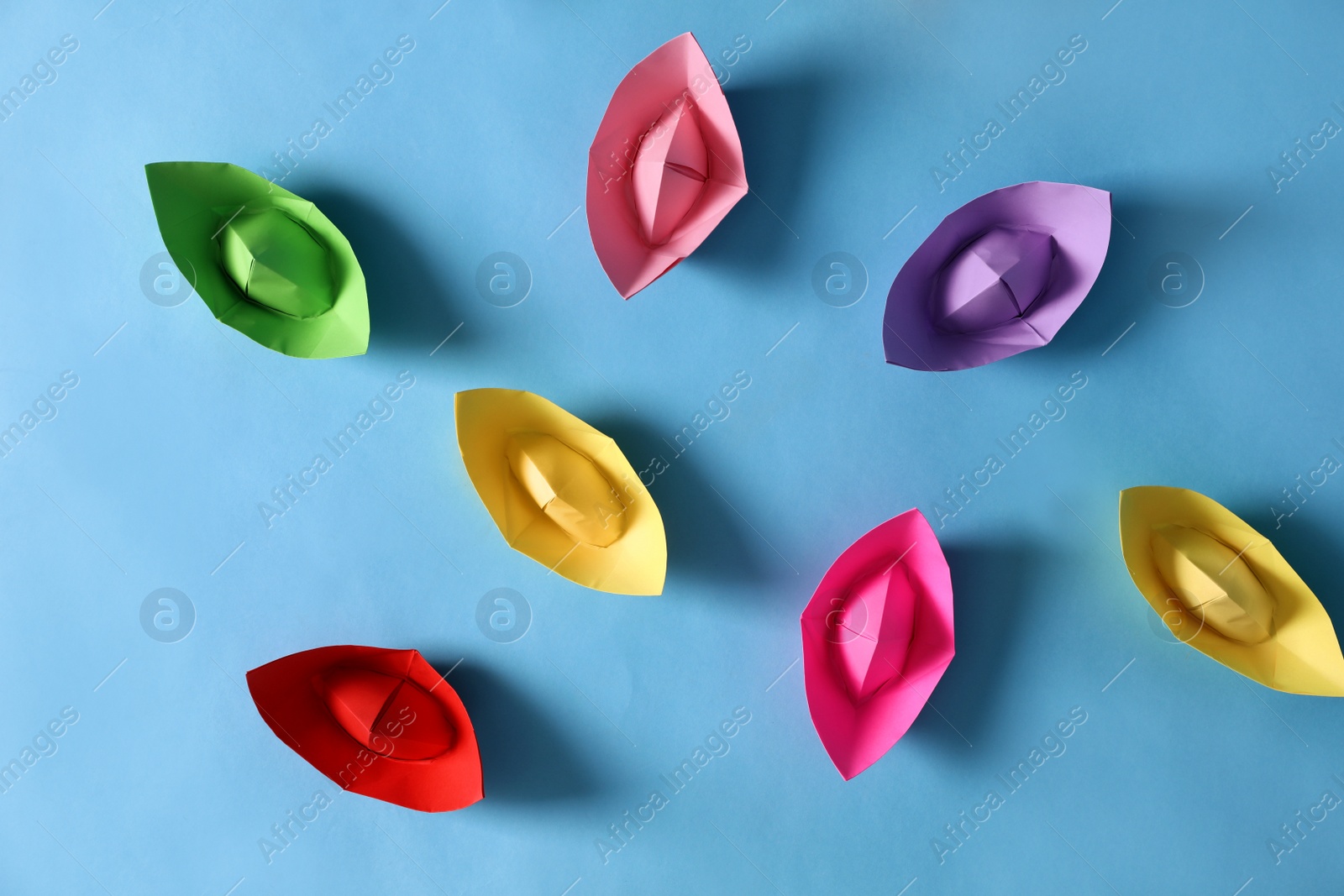 Photo of Colorful paper boats on light blue background, flat lay. Diversity concept