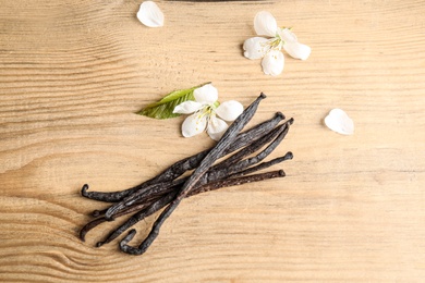 Flat lay composition with aromatic vanilla sticks and flowers on wooden background