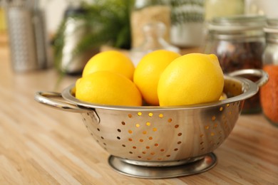 Fresh lemons in colander on wooden countertop. Kitchen interior element