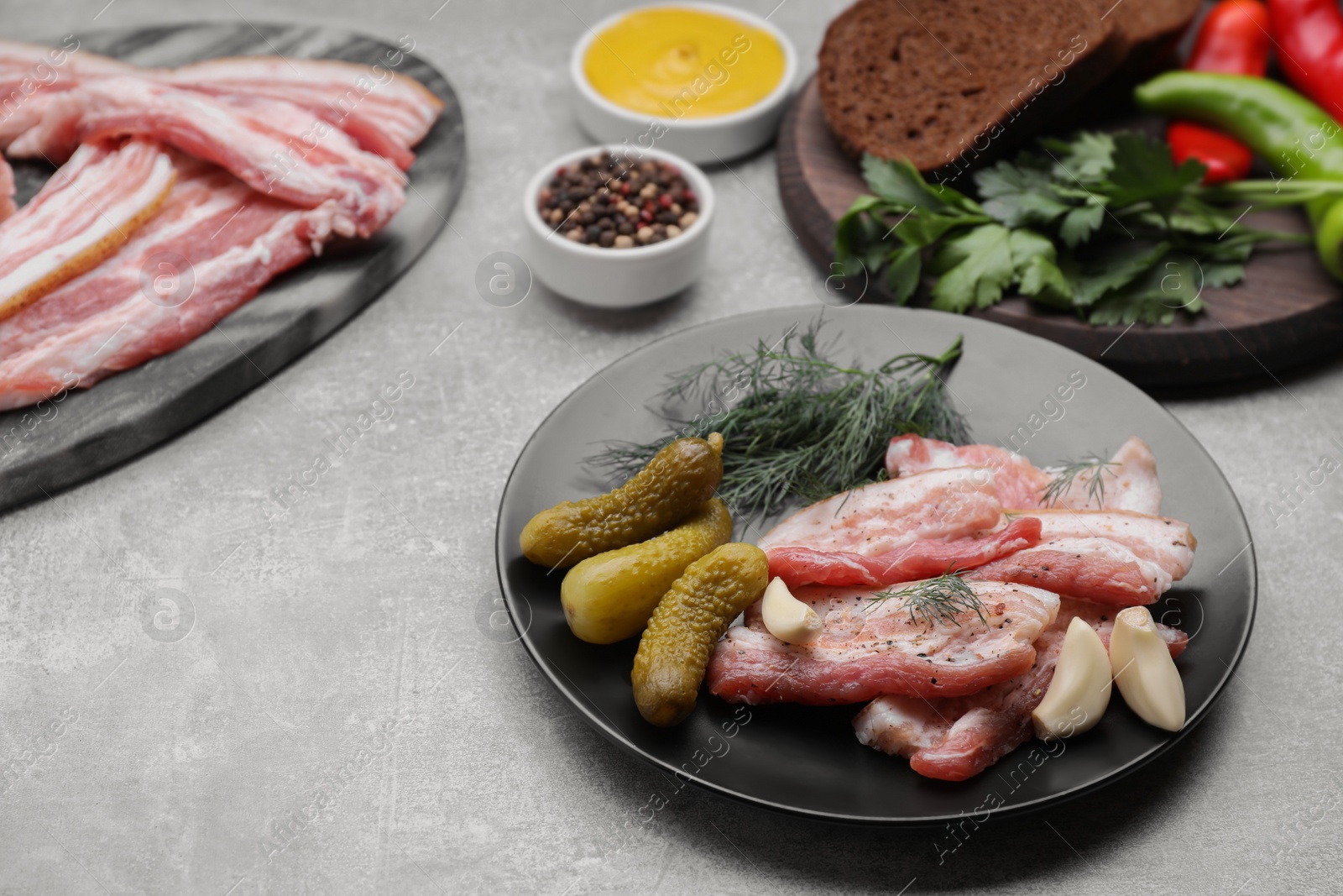 Photo of Tasty pork fatback, pickled cucumbers and ingredients on grey table