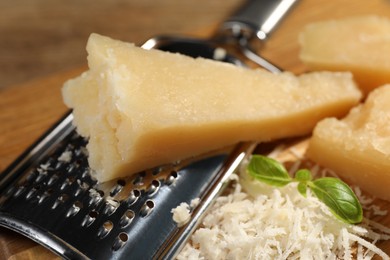 Photo of Grated parmesan cheese with basil near grater, closeup
