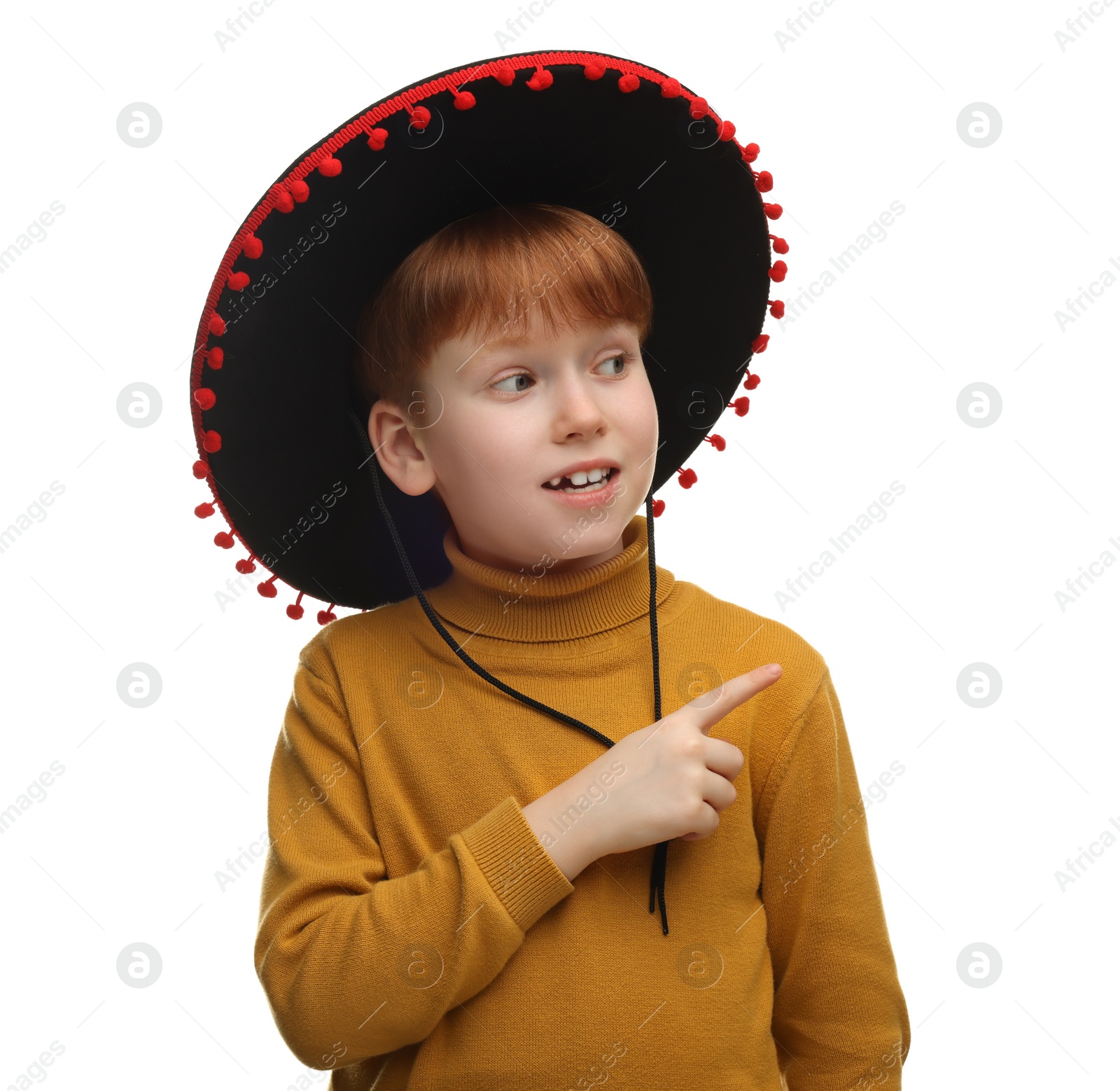 Photo of Cute boy in Mexican sombrero hat pointing at something on white background