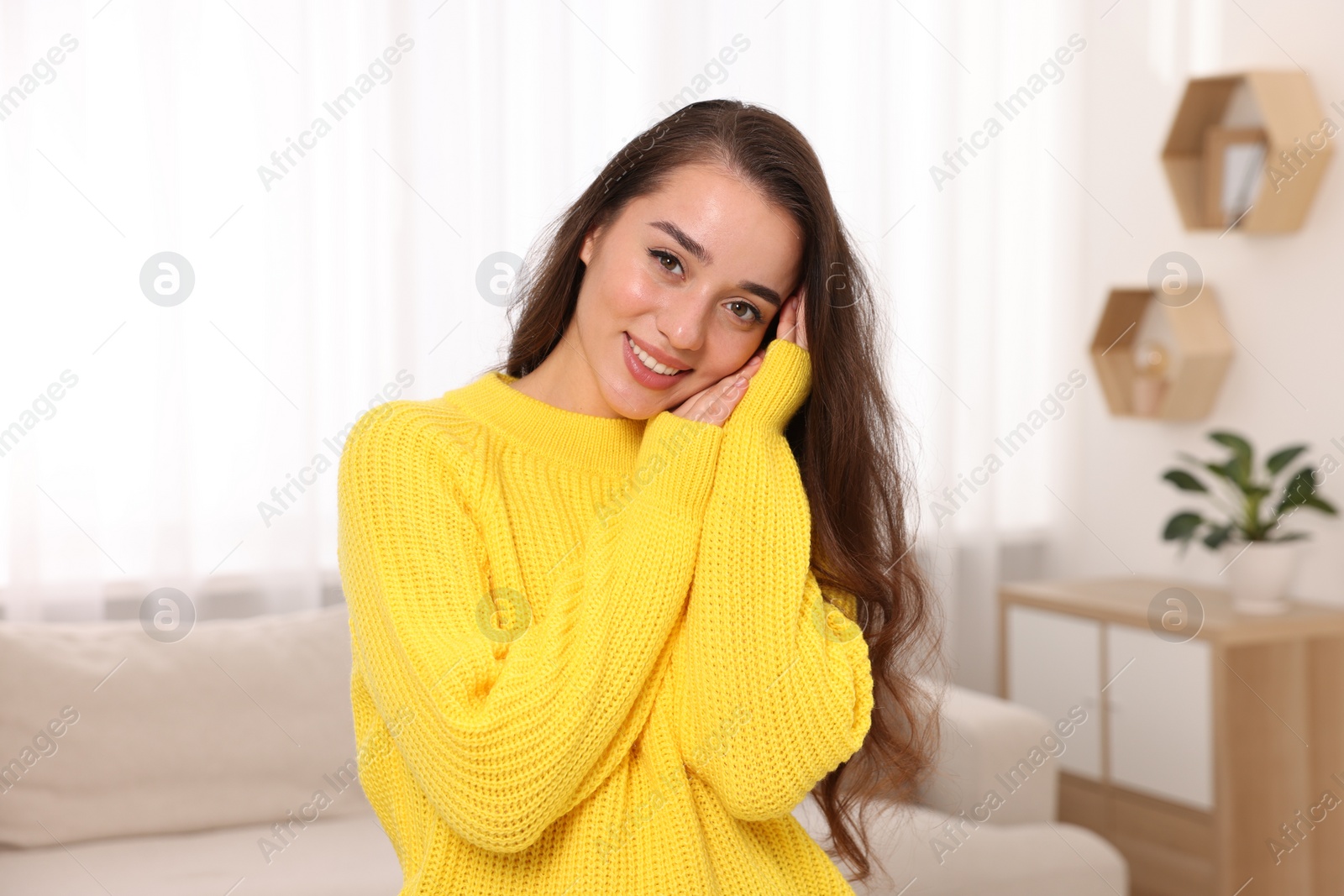 Photo of Beautiful young woman in stylish warm sweater at home