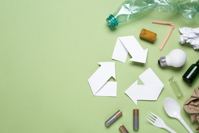 Photo of Recycling symbol and garbage on light green background, flat lay. Space for text